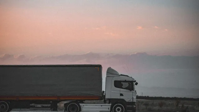 Camión de carga circulando por una carretera al atardecer.