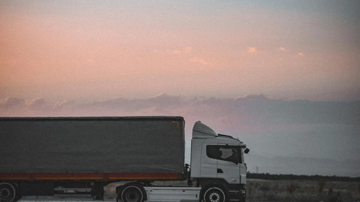 Camión de carga circulando por una carretera al atardecer.
