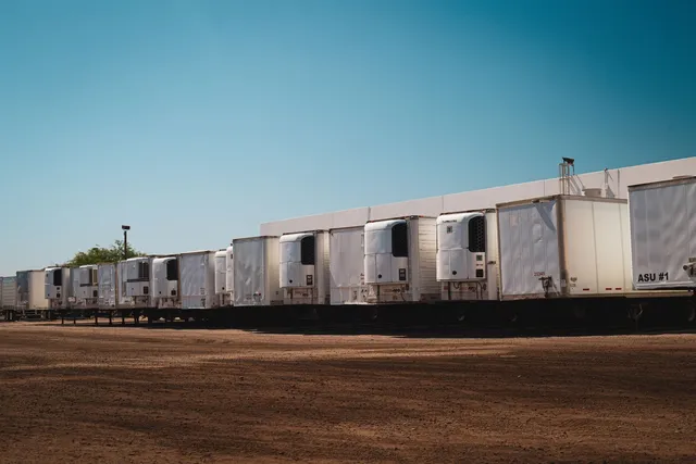 Camiones refrigerados estacionados en un patio industrial de logística.