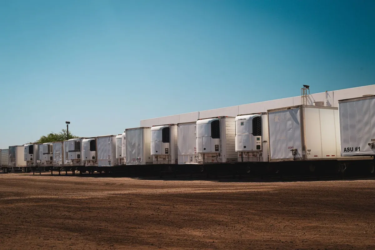 Camiones refrigerados estacionados en un patio industrial de logística.