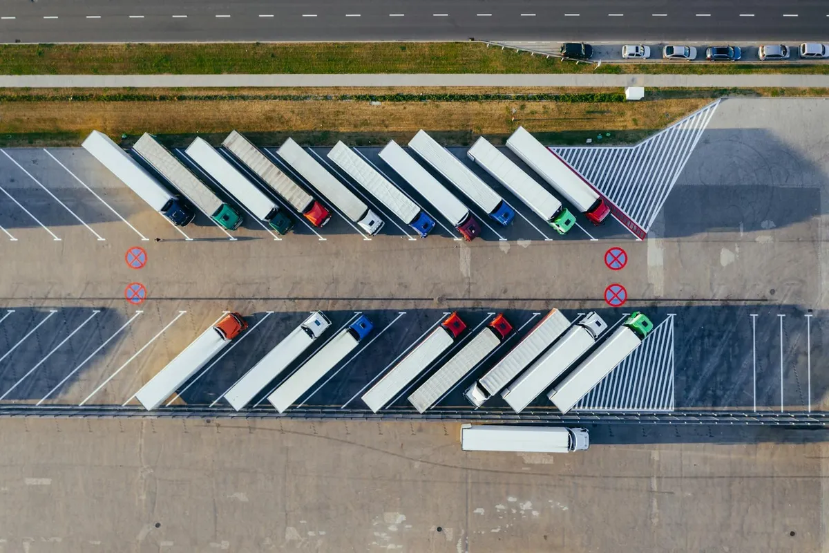 Vista aérea de varios camiones de carga estacionados en un patio de logística.