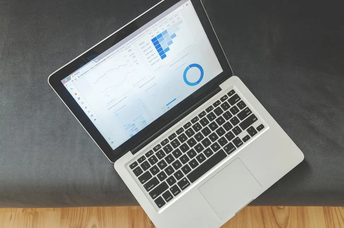 Laptop sobre un sofá mostrando un tablero con gráficas y datos de análisis.